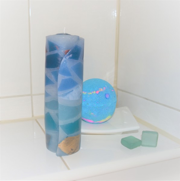 blaue Kerze mit blauer Badekugel vor weißem Hintergrund